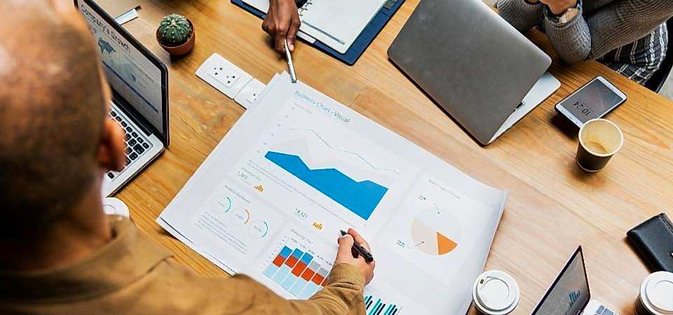 Google Adwords çalışmaları bulunur sarı masanın üstünde bulunan bilgisayar ve insanların  kalemlerinin yanında